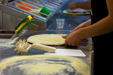 rolling out pizza bases from dough with pizza hands in a restaurant close-up