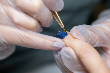 manicure master close-up is distributed with a thin nail brush gel polish on the surface of the nail