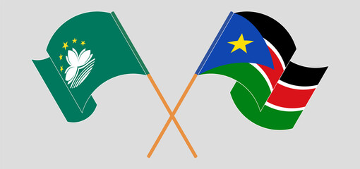 Crossed and waving flags of Macau and South Sudan