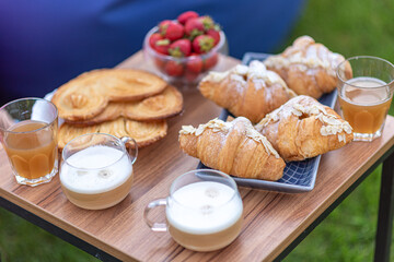 Breakfast outside. Croissants and coffee for adults, buns and compote for children. Strawberries in a vase