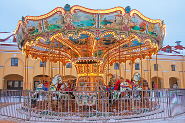 Illuminated bright beautiful carousel with toy horses at festive winter fair
