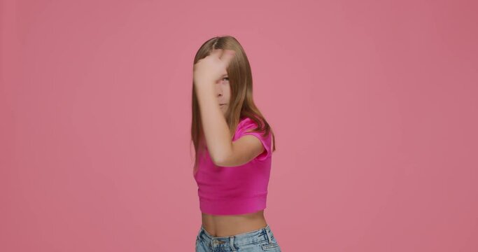 Funny joyful child girl show rock gesture by hands, having fun. Kid rocker make death horns sign on pink background