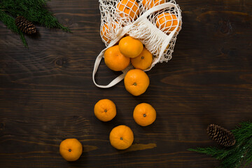 Fresh mandarin oranges fruit or tangerines on a wooden table. Christmas composition. Mandarin oranges in organic cotton mesh bag. Grocery shopping fabric net bag. No plastic bag. - 477521832