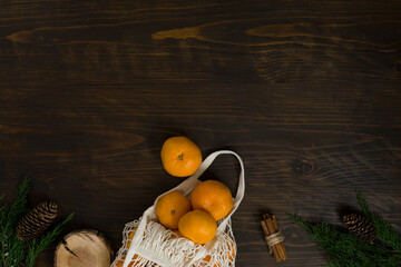 Fresh mandarin oranges fruit or tangerines on a wooden table. Christmas composition. Mandarin oranges in organic cotton mesh bag. Grocery shopping fabric net bag. No plastic bag. - 477521851