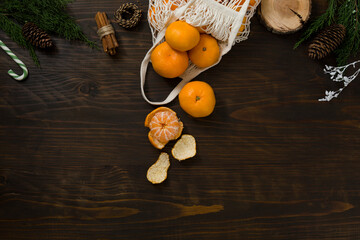 Fresh mandarin oranges fruit or tangerines on a wooden table. Christmas composition. Mandarin oranges in organic cotton mesh bag. Grocery shopping fabric net bag. No plastic bag. - 477521853