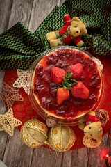 Whole strawberry cheesecake on the Christmas table. With dolls, lights and decorations that remind you of Christmas