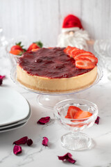 Whole strawberry cheesecake on the Christmas table. With dolls, and crystal accessories and decoration that reminds Christmas