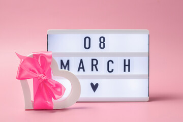 Postcard concept for March 8 for girls. White heart with pink bow and light box with the date of World Women's Day.