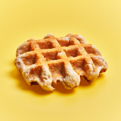 Single delicious waffle over yellow background