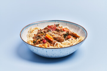  Plate of delicious spaghettis with meat and vegetables over blue background