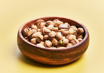  Bowl of pistachios over yellow background
