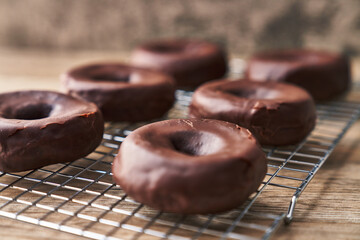  Oven tray with chocolate doughnuts on a wooden surface