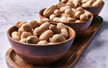  Bowls of peanuts with shell on a marble surface