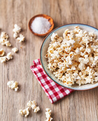  Bowl of salty popcorns on a wooden surface