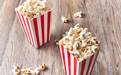  Two packs of salty popcorns on a wooden surface