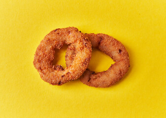  Two breaded onion rings on a yellow background