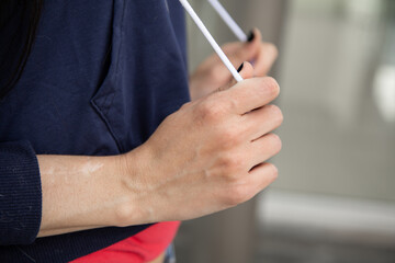 hand of a person holding the cord of his sports sweater, detail of the knuckles, wrist and hand texture, gesture of nervousness, studio