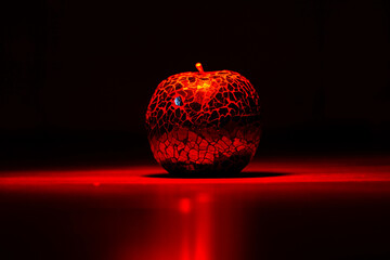 Glass apple in red light on black backgroud