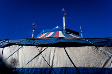 Wrinkled plastic tarp covers a tent for events such as a circus, with a sky background.