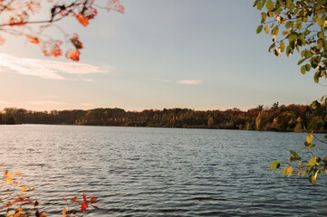 Beautiful autumn landscape view with Seneca lake surface reflecting sunset sky and yellow orange...