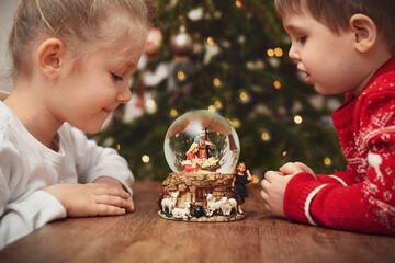 Children looking at a glass ball with a scene of the birth of Jesus Christ
