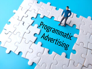 Text Programmatic Advertising written on blue background with white puzzle and miniature people.