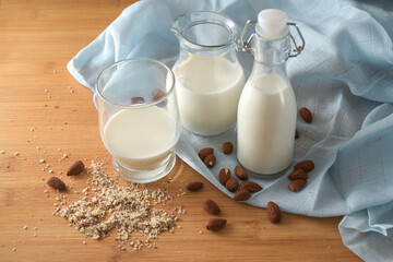 Vegan milk from almonds in glass jars on a blue napkin and a wooden table, environmentally friendly alternative to animal dairy products, copy space