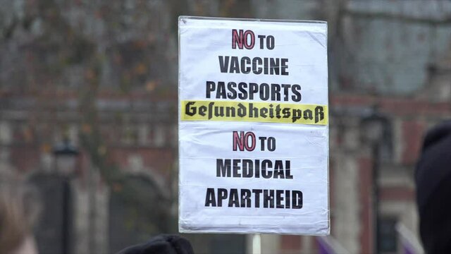 A white protest placard says “No to vaccine passports, no to medical apartheid” with the German word “Gerfundheitspar” in the middle, meaning “Health-saving” on an anti-Covid vaccine protest.