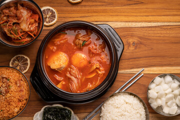 Kimchi soup in hot iron pot with rice and Kimchi pickle on wooden table, Korean traditional Kimchi soup with Tofu mushroom hot pot.