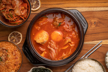 Kimchi soup in hot iron pot with rice and Kimchi pickle on wooden table, Korean traditional Kimchi soup with Tofu mushroom hot pot.