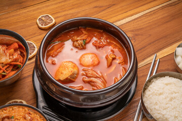 Kimchi soup in hot iron pot with rice and Kimchi pickle on wooden table, Korean traditional Kimchi soup with Tofu mushroom hot pot.