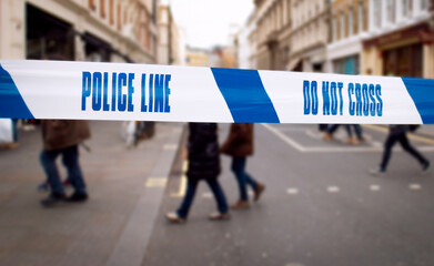 Police line – Scene of a generic urban downtown area cordoned off by blue tape reading ‘DO NO...