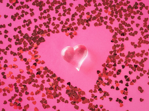 Abstract image of a glass heart on the background of scattered small hearts. The concept of Valentine's Day.