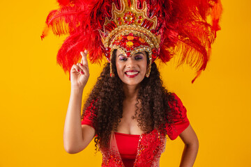 Portrait of afro brazilian woman in carnival outfit with fingers crossed wishing luck. Carnival...