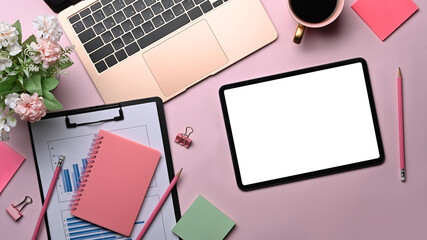 Above view digital tablet, laptop computer, paperwork and supplies on pink background.