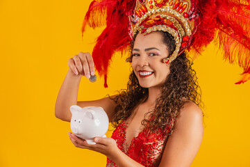 Carnival dancer woman holding a piggy bank in hands. Concept of saving for carnival