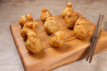 Ekado or ekkado is processed fish or shrimp meat wrapped in dumpling skin and shaped like a bag filling with cheese whose upper part is tied with chives.