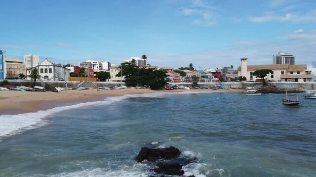 Drone flying near the Sea in Coastline with waves, rocks and boats. Red River Beach in Salvador of Carnival, state of Bahia Brazil.