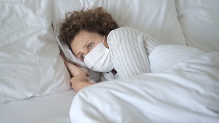 Isolated woman suffering from coronavirus infection, fever, cough, pain, staying in bed on covid-19 quarantine