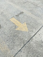 yellow street arrow sign on cement floor at day time