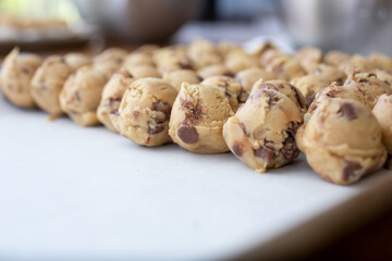 A view of a baking sheet pan of chocolate chip cookie dough balls.