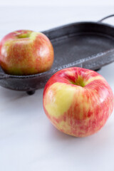 A view of honeycrisp apples in a rustic metal tray, on a white background.