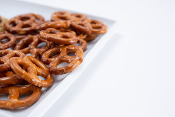 A view of a plate of pretzels, on the left side of the frame, on a white background.