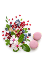 A scattering of juicy berries, flower and macarons.