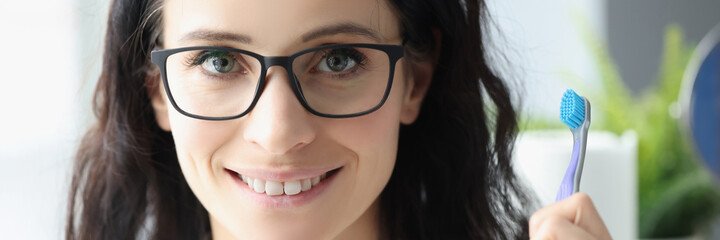 Young woman dentist in glasses holding toothbrush in her hands