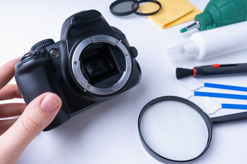 The photographer holds his DSLR camera without a lens before cleaning the sensor