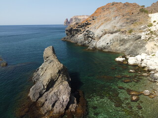 Aerial view from above on calm azure sea and volcanic rocky shores. Small waves on water surface in motion blur. Nature summer ocean sea beach background. Nobody. Holiday, vacation and travel concept