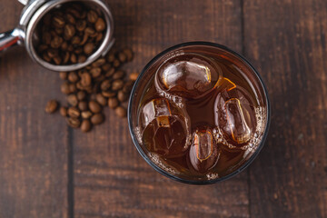 A cup of Iced Americano Coffee with ice cubes placed on a wooden table in a coffee shop. Top view of a glass of coffee.