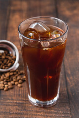 A cup of Iced Americano Coffee with ice cubes placed on a wooden table in a coffee shop. Top view of a glass of coffee.