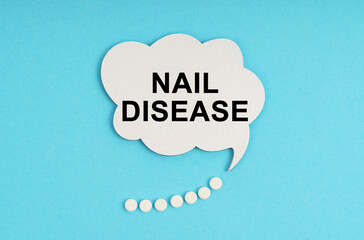 On a blue table are pills and a white plate with the inscription - NAIL DISEASE